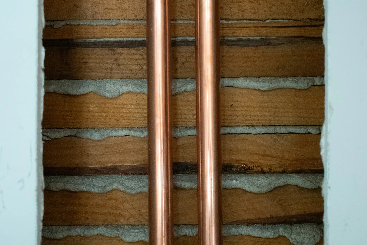 Two copper water pipes exposed in an opened wall
