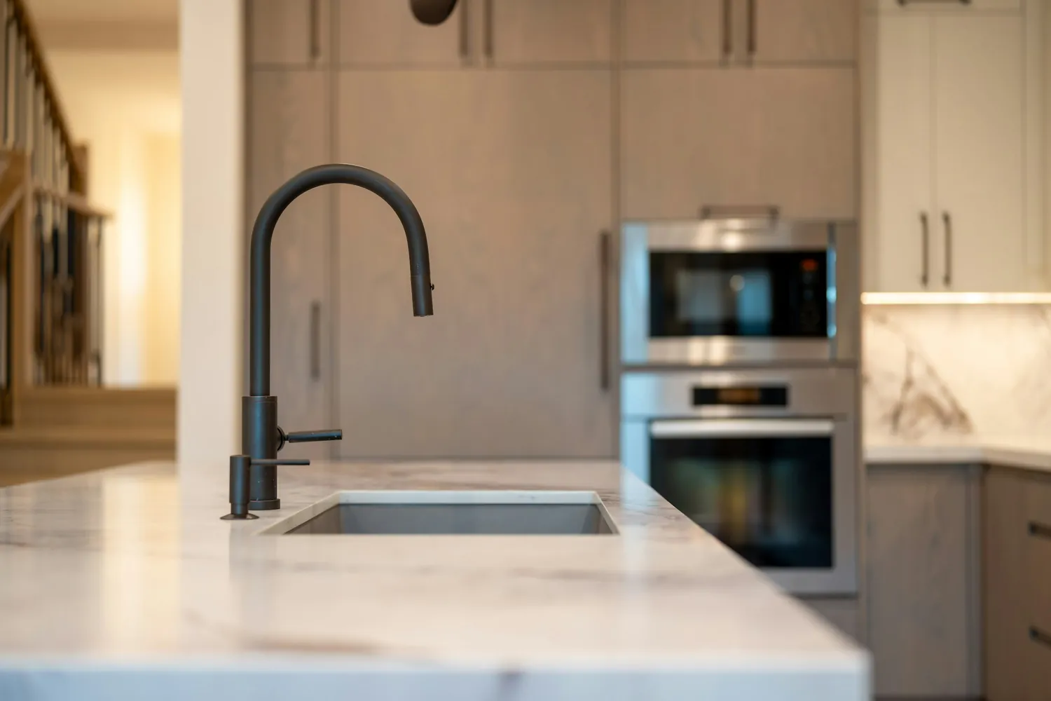 Modern kitchen with a black faucet, stone countertop and built-in ovens
