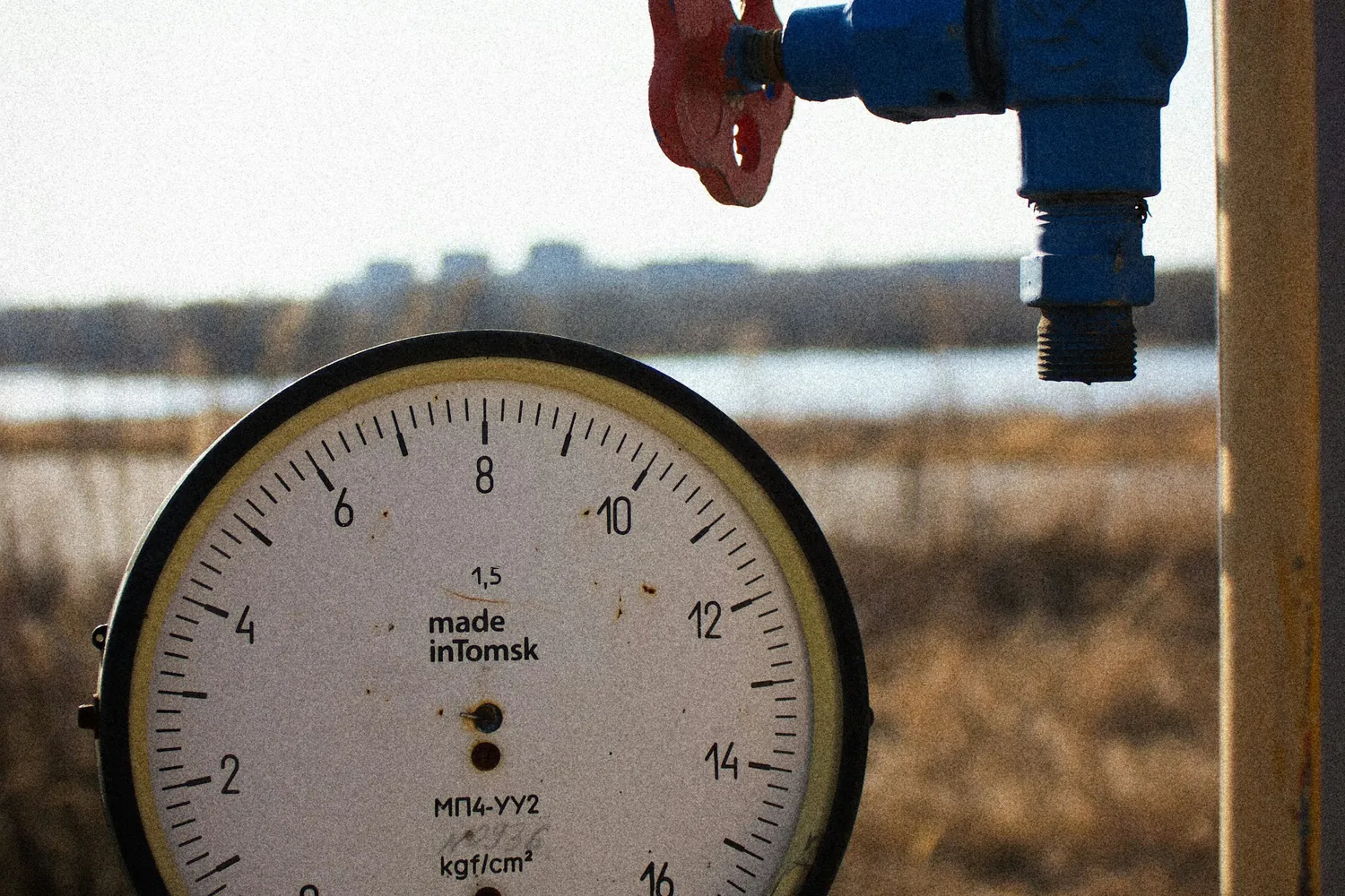 Pressure gauge and blue valve on an outdoor water pipe