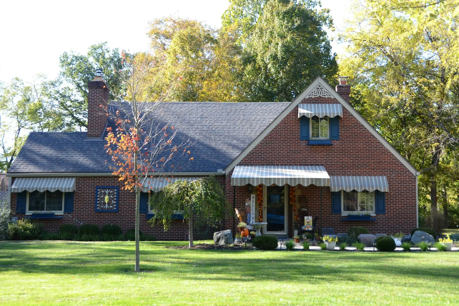 Red brick single-family home with a green lawn and shade trees